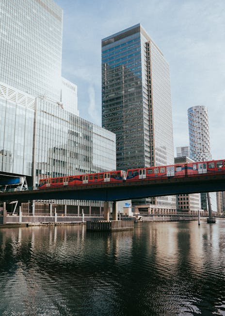 A modern multi-storey glass office building with curved, reflective facade panels presenting a sleek, contemporary appearance, situated among other high-rise structures in an urban setting. The buildi